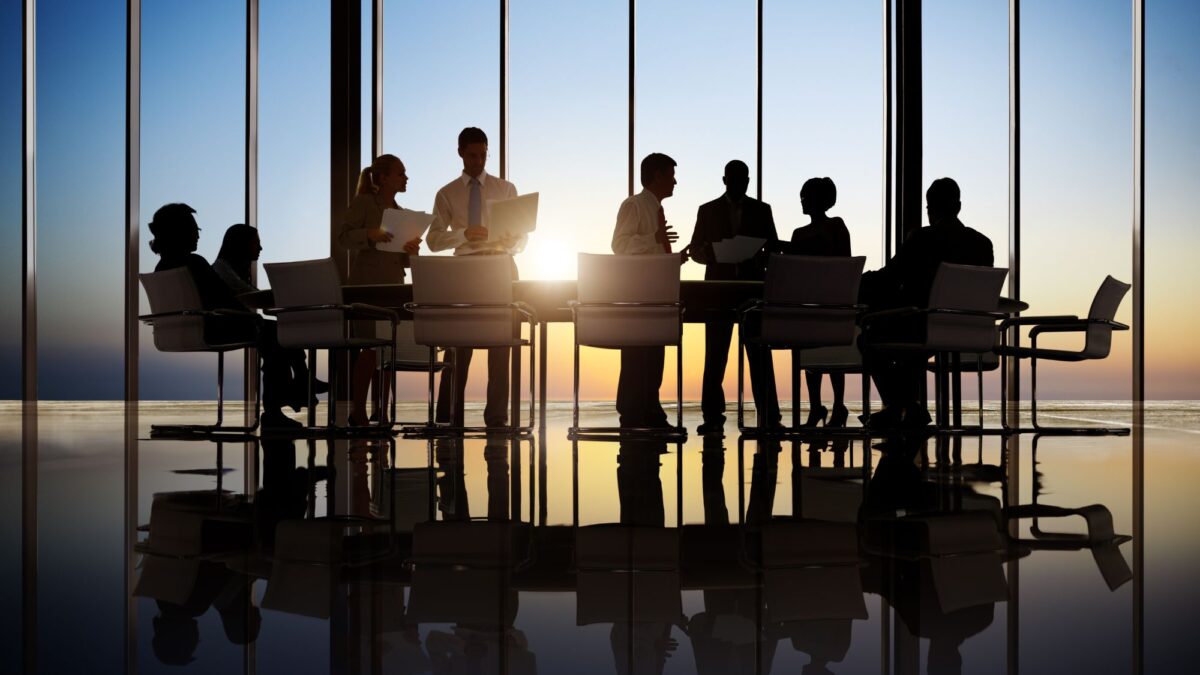 A group of employees discussing business operations and CRM solutions and a beautiful sunset in the back