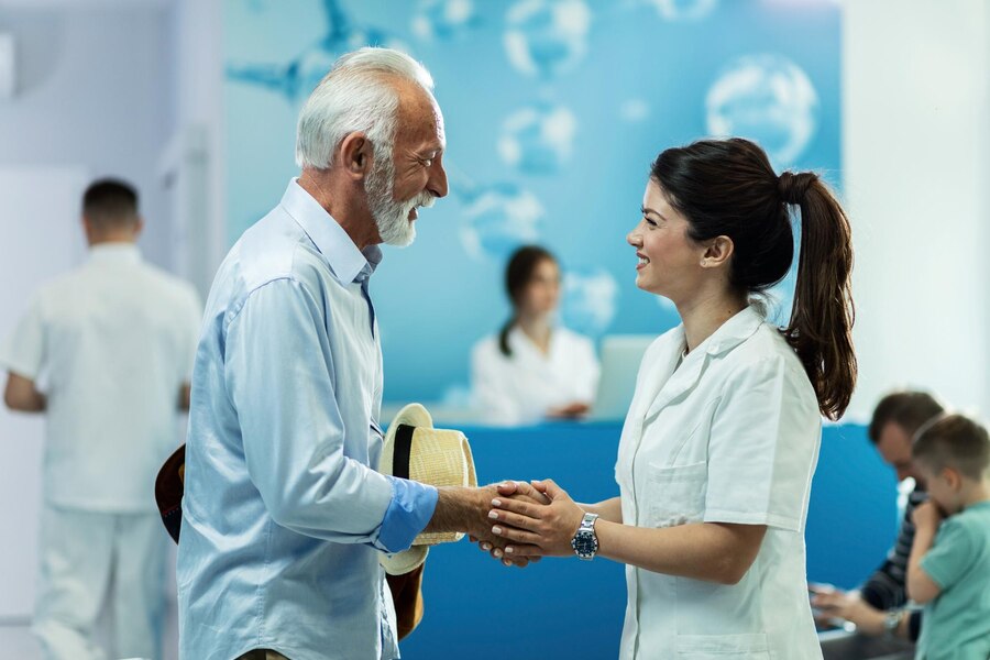 happy-senior-man-handshaking-with-female-doctor-while-talking-lobby-clinic