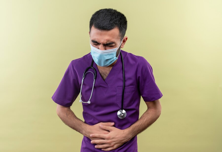 sick-young-male-doctor-wearing-purple-surgeon-clothing-stethoscope-medical-mask-grabbed-aching-stomach-isolated-green-background_