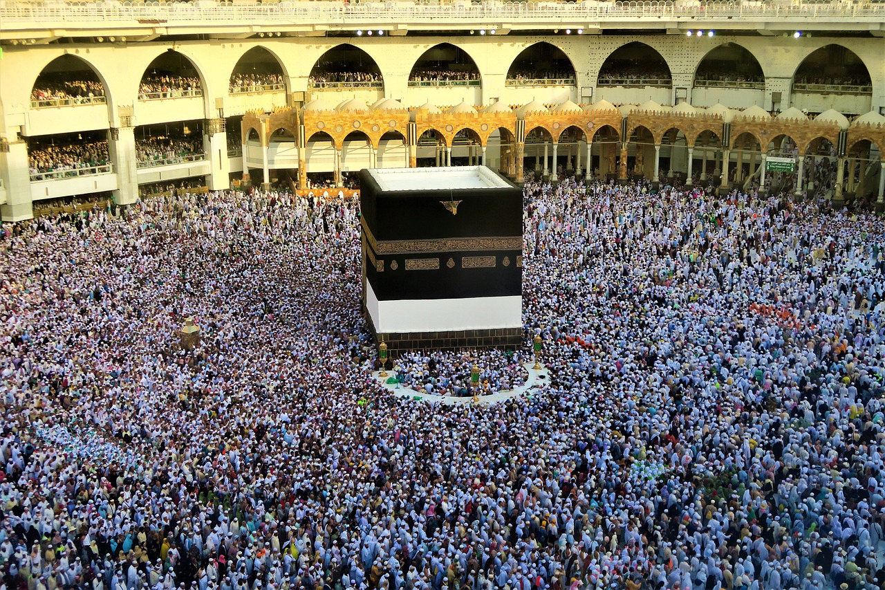 Pilgrims performing Tawaf around the Kaaba in the Masjid al-Haram mosque in Mecca, Saudi Arabia, with crowded worshippers and mosque architecture in the background.